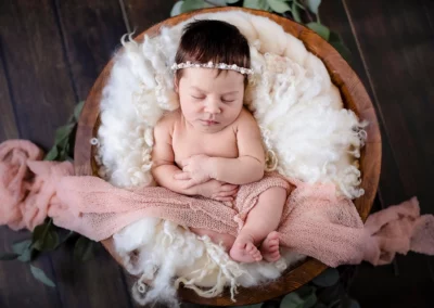 Neugeborenen-Fotoshooting in rustikaler Holzwanne mit dekorativen Elementen