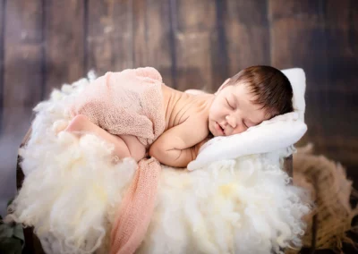 Niedliche Neugeborenen-Pose im gemütlichen Bettchen